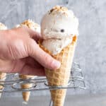 hand reaching for coconut ice cream in a waffle cone.