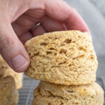 woman grabbing whole wheat biscuits from a cooling rack.