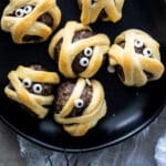 Simple Meatball Mummies For Halloween on a black plate.
