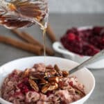 Woman pouring maple syrup over cranberry oatmeal.