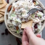 Chicken salad with cranberries and pecans in white bowl.