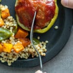 Woman cutting meatloaf stuffed bell peppers.