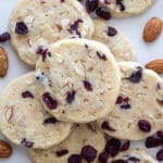 Cranberry almond cookies stacked on a surface.
