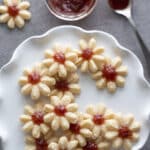 Spritz cookies with jam on white platter.