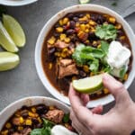 Weight watchers taco soup recipe in a white bowl topped with cilantro and sour cream.