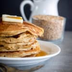 Einkorn Pancake Recipe stacked on plate with maple syrup on them.