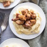 Blackened pork tenderloin on top of mashed potatoes served on white plates.
