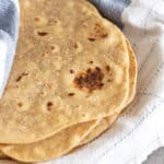 Kamut tortillas in a dish towel on a white plate.