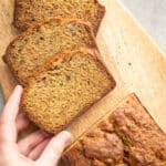 Zucchini carrot banana bread sliced on a wooden cutting board.