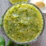 A jar of spicy green salsa on the table.