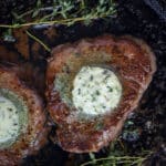 A cast iron filet mignon cooked and topped with compound butter.