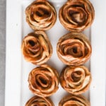 Baked apple rosettes on a white tray.