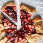 Rhubarb blackberry galette cut into pieces on a parchment lined baking sheet.