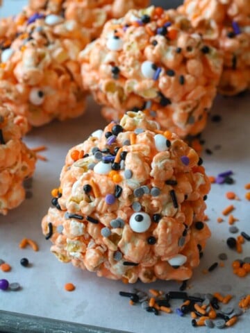 Halloween popcorn balls on a parchment-lined baking sheet.