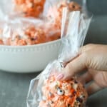 Woman holding a Halloween popcorn ball in a treat bag.