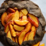 Baked peach galette on parchment paper.