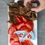 Woman grabbing rye crisps off a white serving plate.