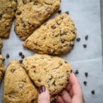 Women grabbing a Chocolate Chip Whole Wheat Scone of a baking sheet.