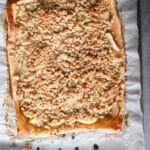 Apple slab pie on a lined baking sheet.