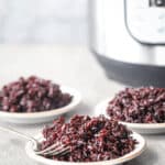White plate with black rice on them with an Instant Pot in the background.