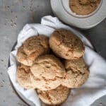 Buttermilk biscuits in a bowl with a white cloth underneath.