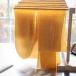 Spelt pasta hanging on a drying rack.