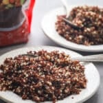 Cooked tri color quinoa on a small white plate.