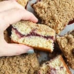 Woman holding a piece of blackberry coffee cake.