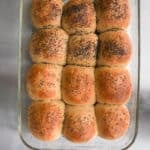 Rye dinner rolls topped with caraway seeds and poppy seeds in a 9x13 glass pan.