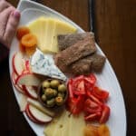 Rye crackers on a white plate with vegetables and fruit.