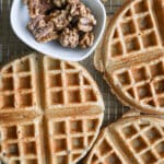 Rye waffles cooling on a cooling rack with candied walnuts on the side.