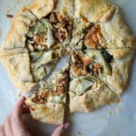 Women grabbing a slice of an artichoke galette.