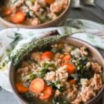 Sausage and farro soup in a ceramic bowl with a sprig of fresh thyme on the side.
