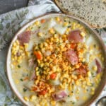 Corn chowder in a ceramic bowl with slices of bread on the side.