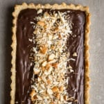 Almond dark chocolate tart with almonds and coconut on top.