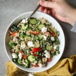 Vegetable barley salad with pearl barley in a white bowl with a yellow napkin on the side.