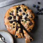 Blueberry cornmeal cake sliced on a surface.