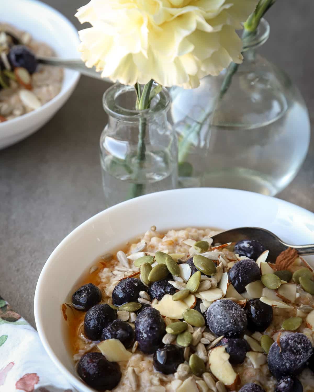 Breakfast porridge in white bowls with a floral napkin next to it.
