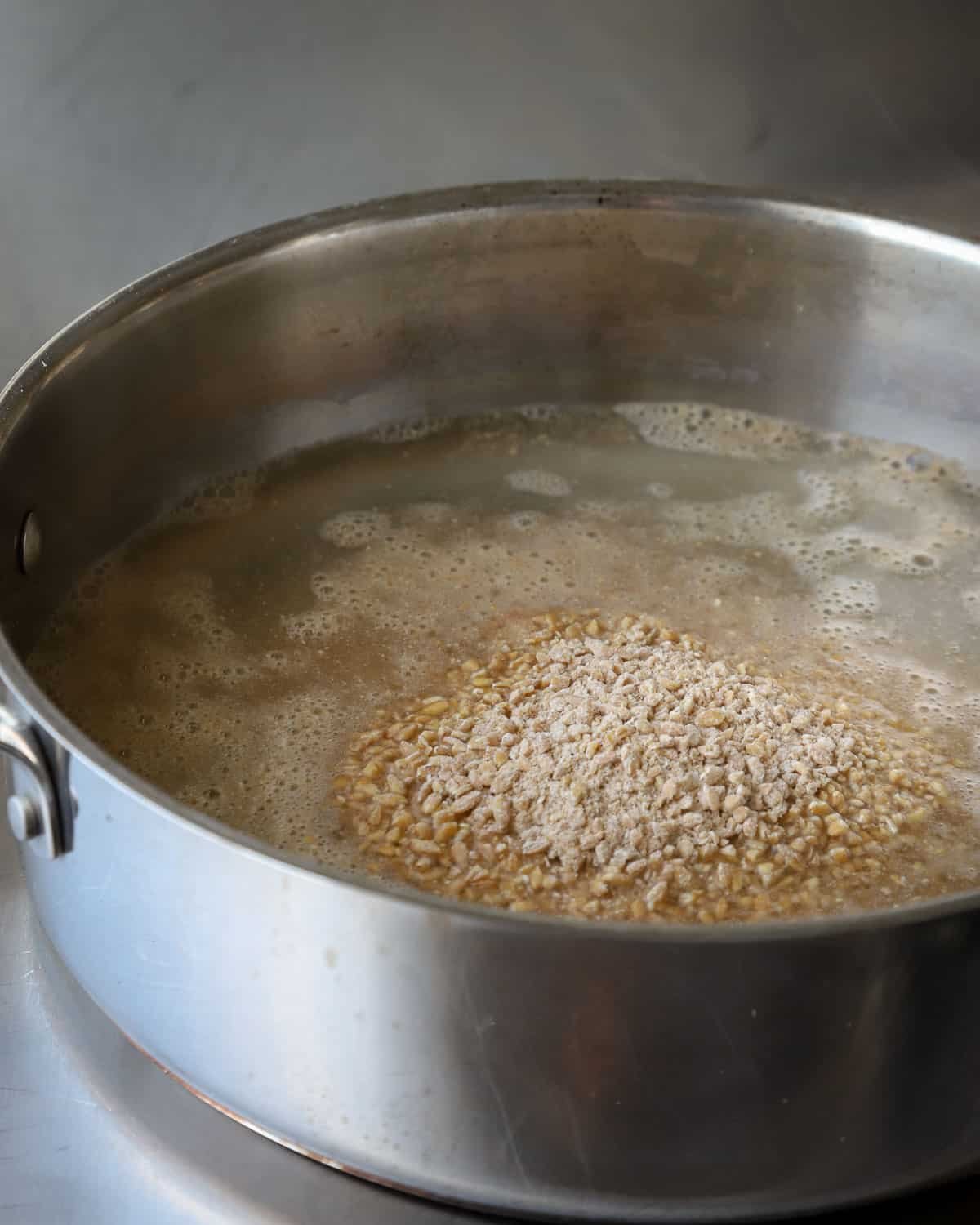 Cracked einkorn cooking in a stainless steel pan.
