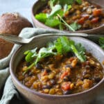 Pumpkin lentil soup in ceramic bowls with spoons in them.