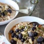 Cracked einkorn porridge in white bowls with a floral napkin beside it.
