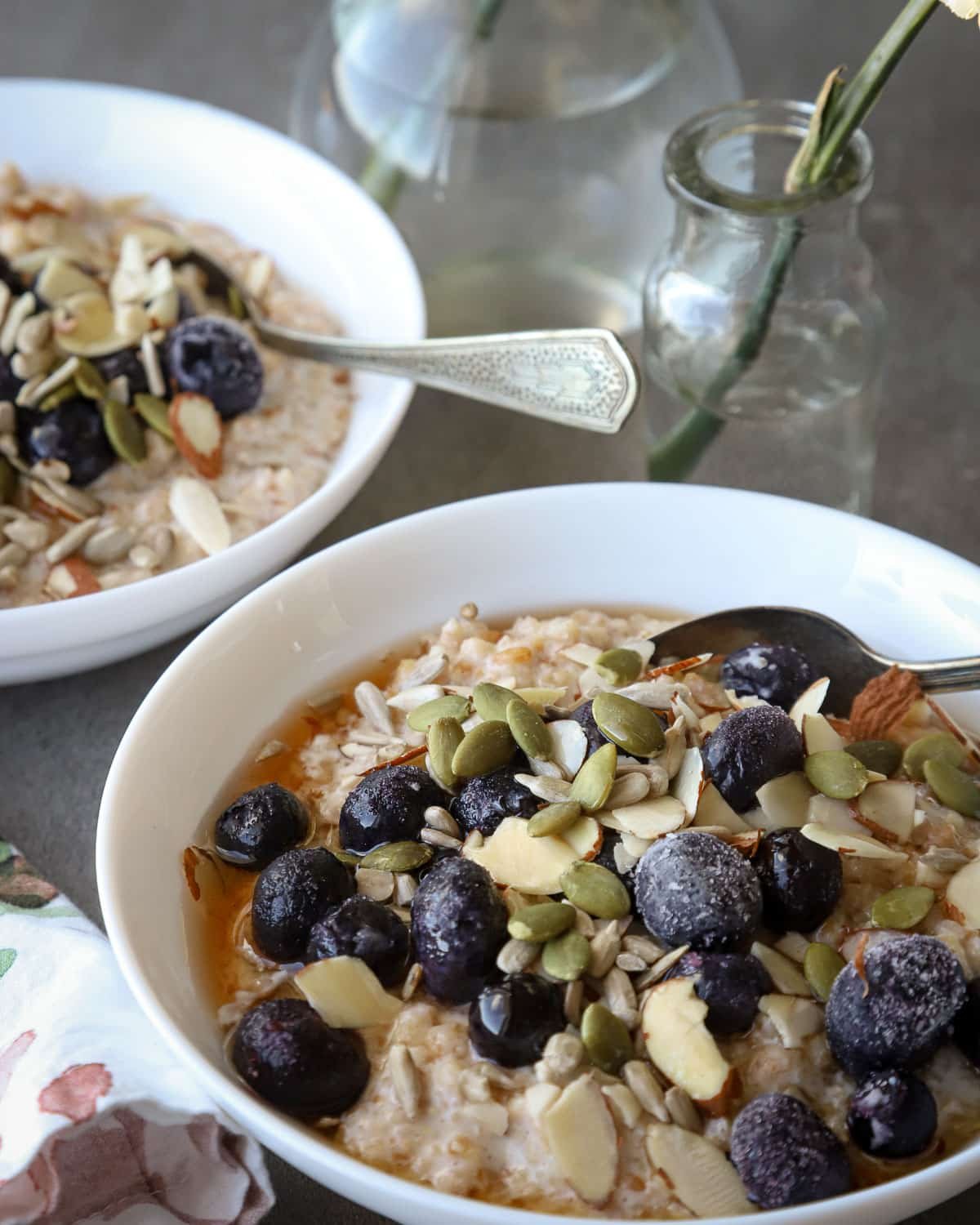 Cracked einkorn porridge in white bowls with a floral napkin beside it.
