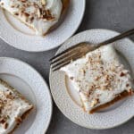 Carrot cardamom cake slices on white plates with an antique fork on the side.