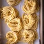Homemade spaghetti on a baking sheet with parchment paper.