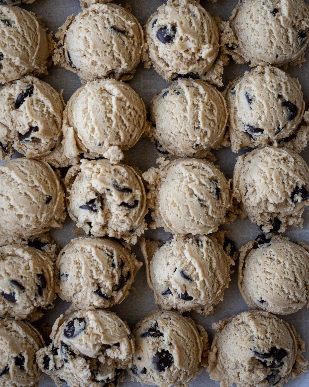 Cookie balls scooped on a baking sheet pan for freezing.