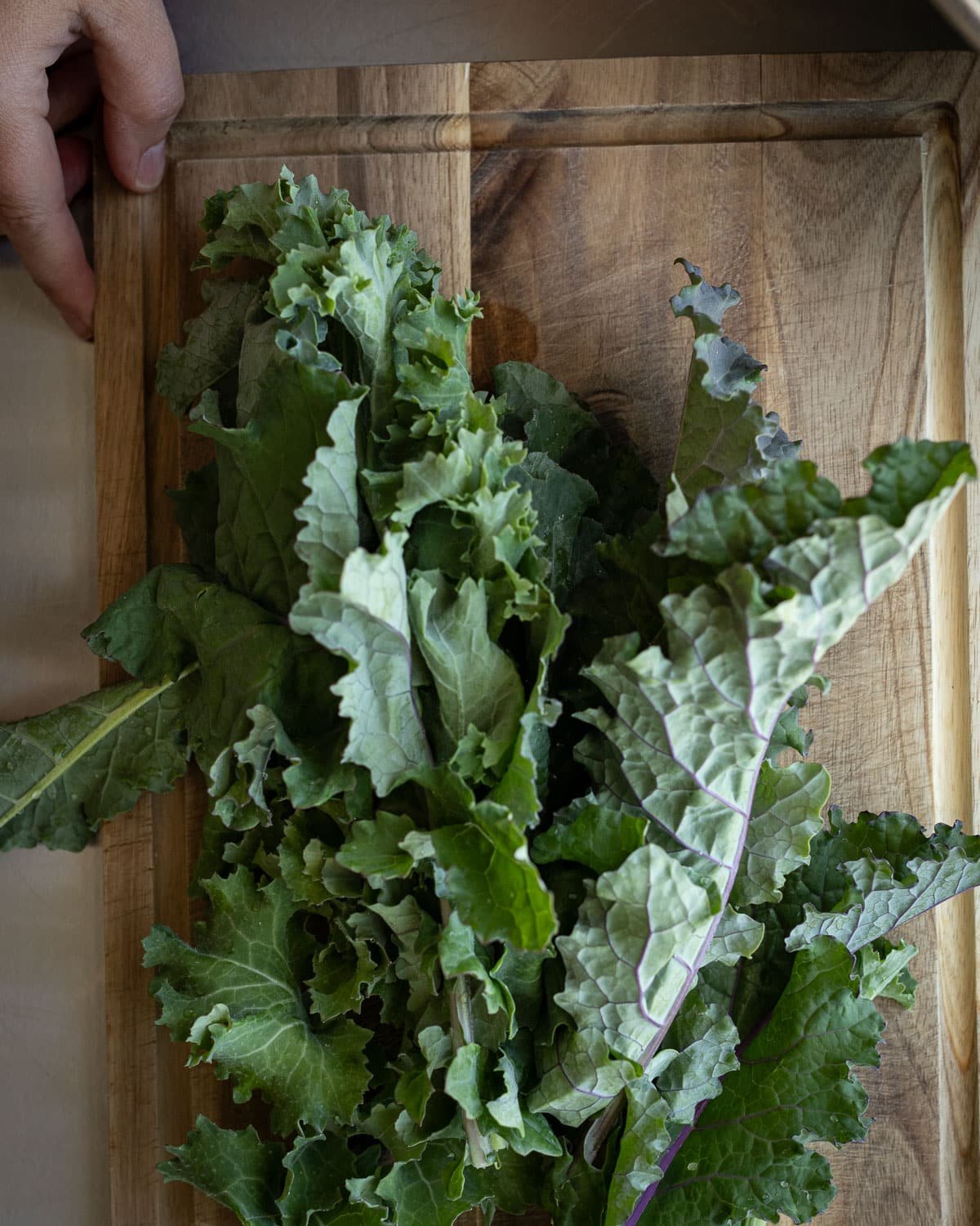 Kale leaves on a wooden cutting board. 
