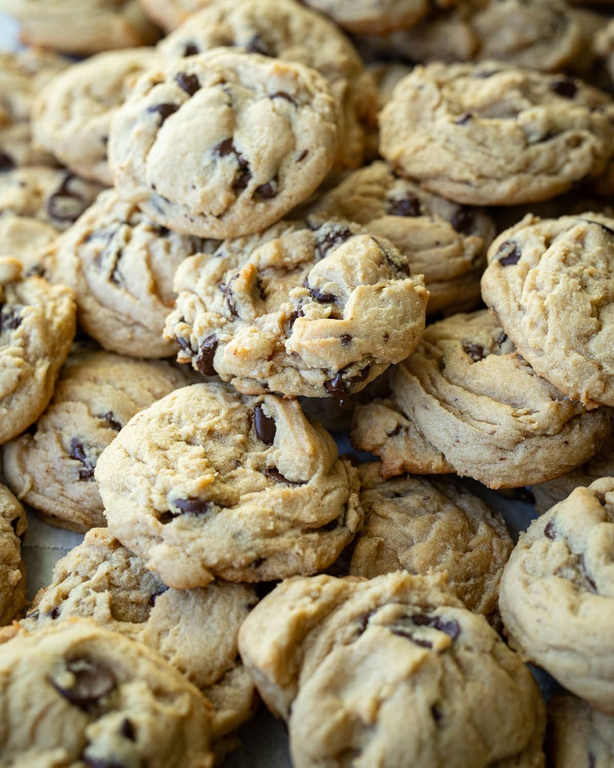 Chocolate chip cookies stacked on parchment paper.