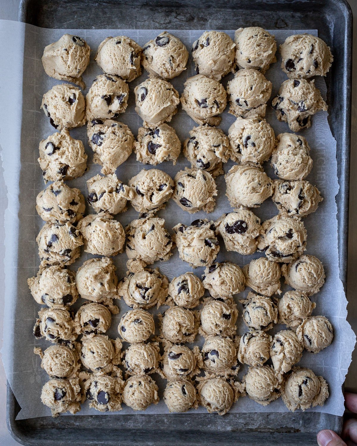 Scooped cookie balls on a baking sheet line with parchment paper.