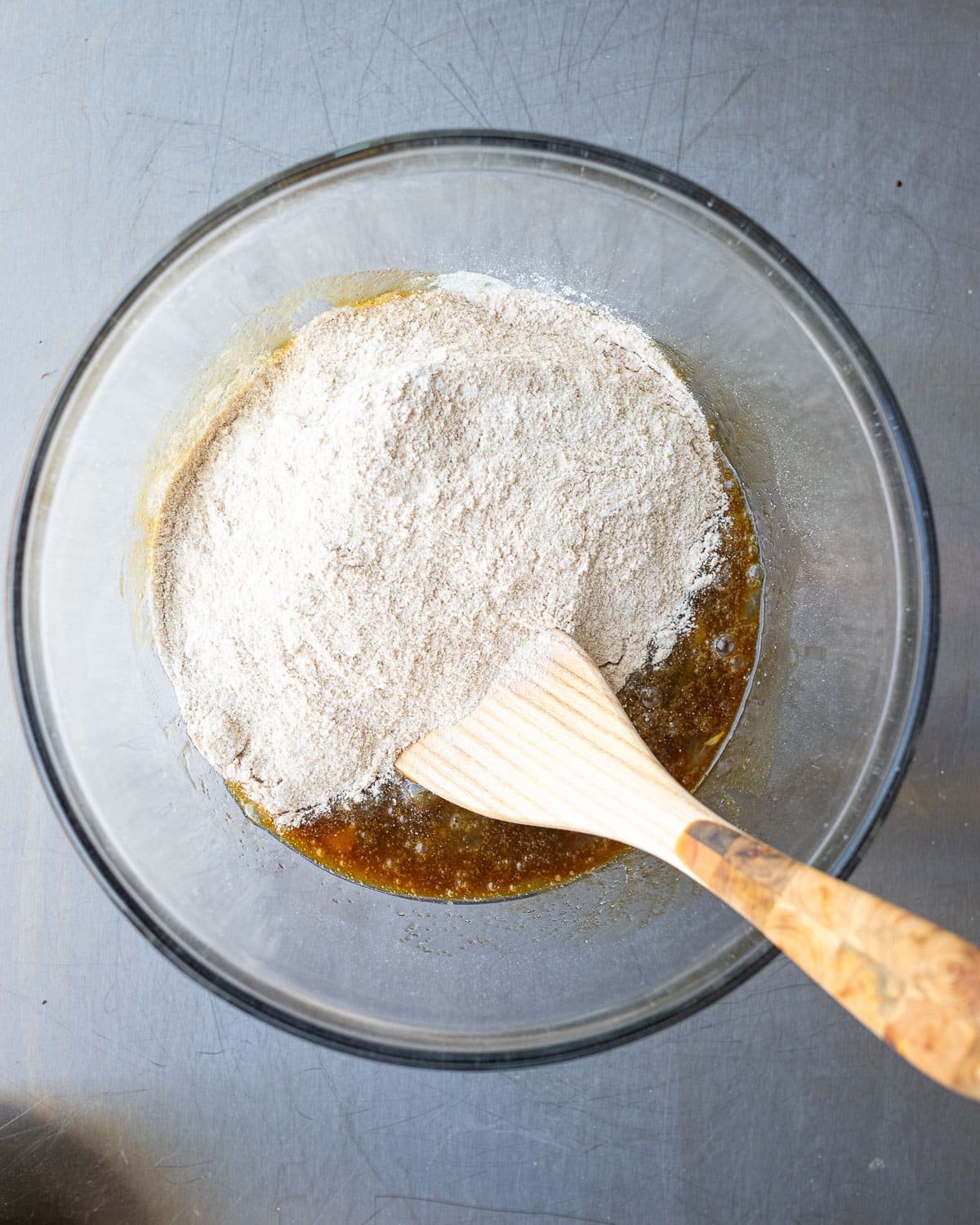Sprouted flour muffin batter in a glass bowl with a wooden spoon. 