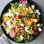Beet and quinoa salad in a black bowl with vintage forks on the side.